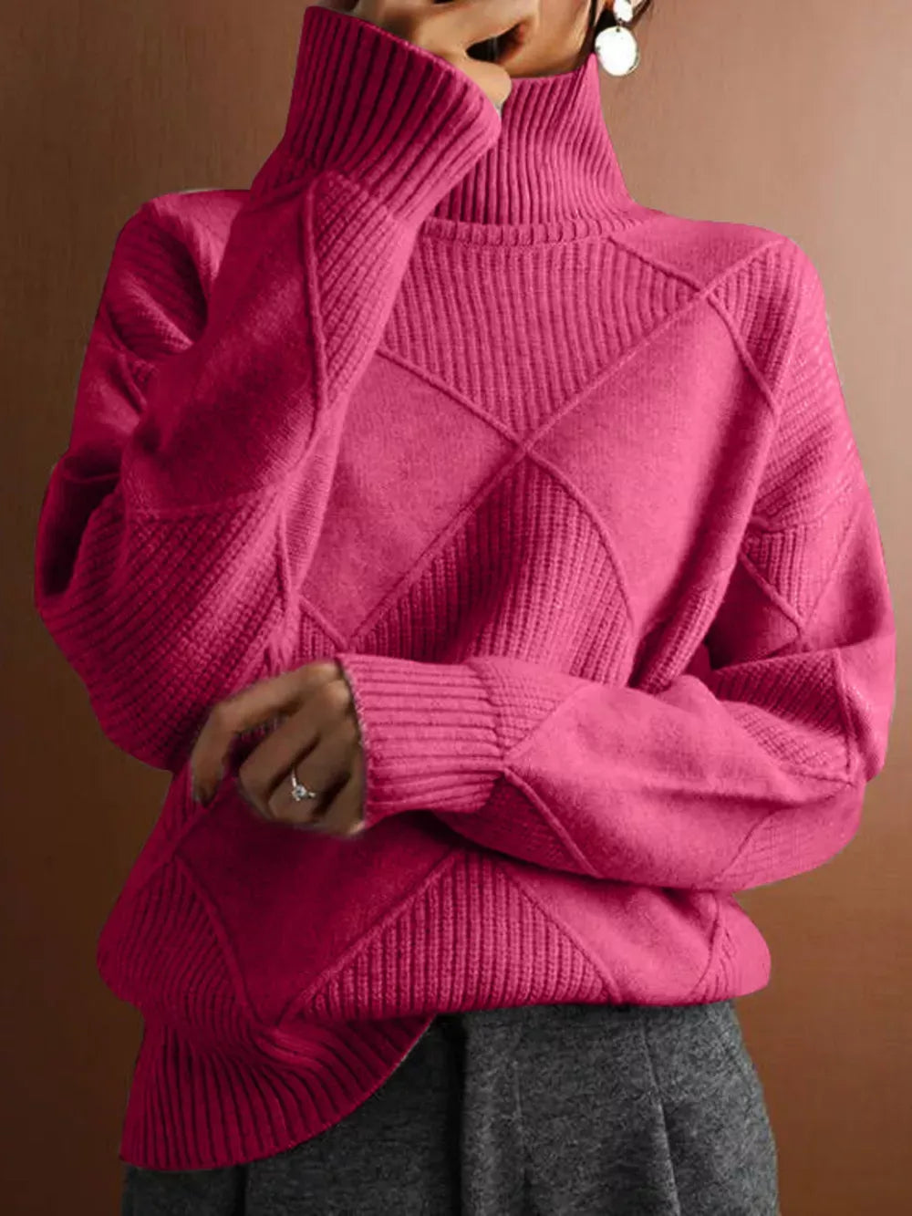 Person wearing a bright pink turtleneck sweater against a brown background
