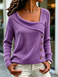 A woman wearing a lavender purple knit sweater with an asymmetrical draped neckline and brown buttons, paired with white pants.