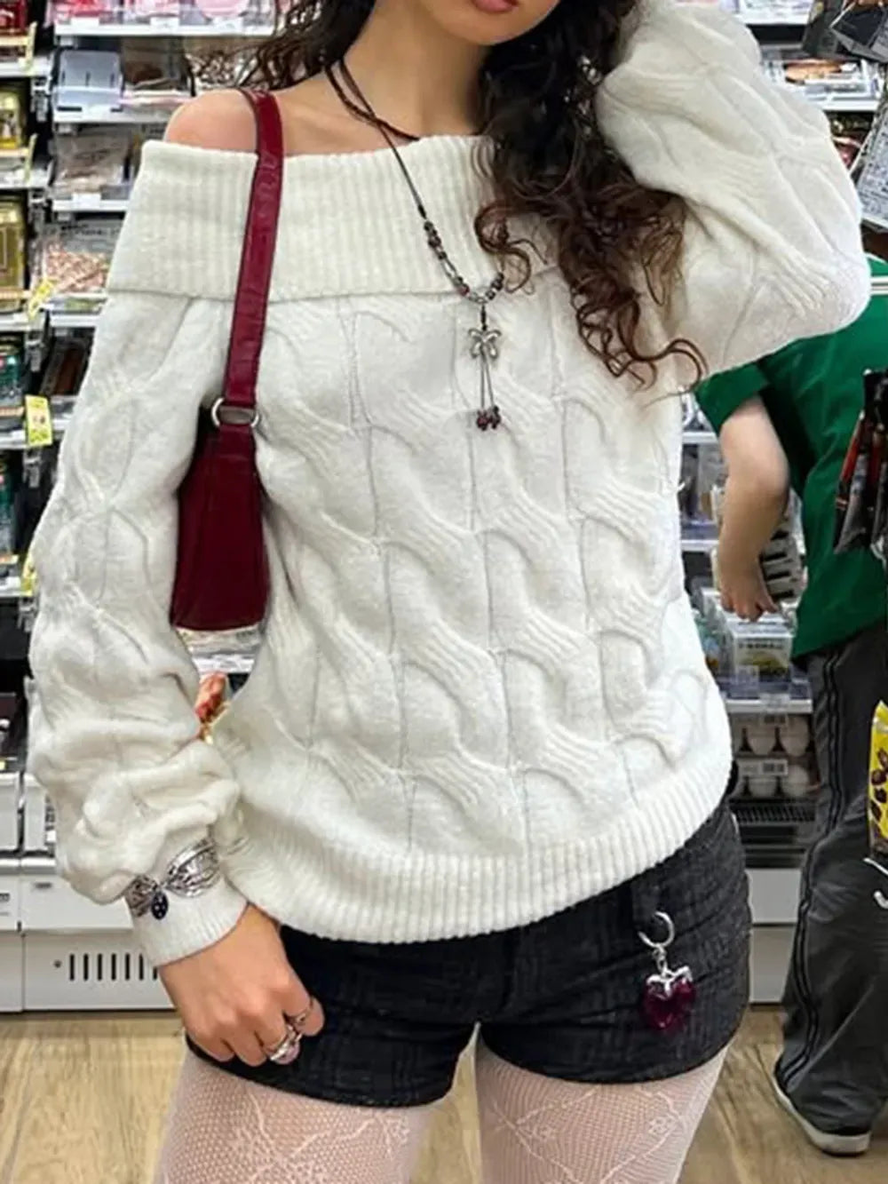 Person wearing a white cable knit sweater in a store setting